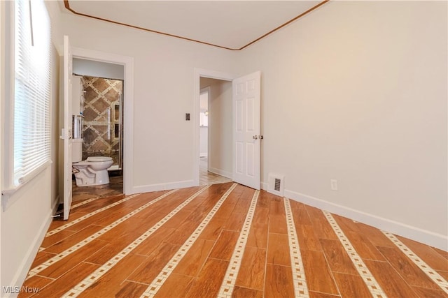 unfurnished bedroom featuring visible vents, baseboards, and wood finished floors