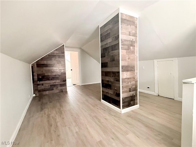 bonus room featuring lofted ceiling, wood walls, baseboards, and wood finished floors