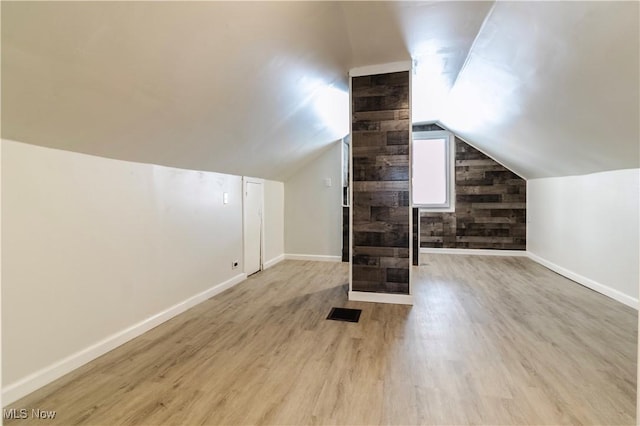 bonus room with lofted ceiling, wooden walls, baseboards, and wood finished floors