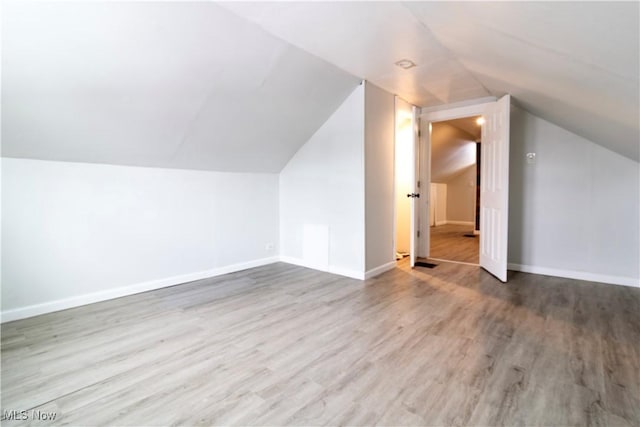 additional living space with lofted ceiling, baseboards, and wood finished floors