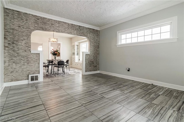 unfurnished dining area featuring arched walkways, visible vents, ornamental molding, a textured ceiling, and baseboards