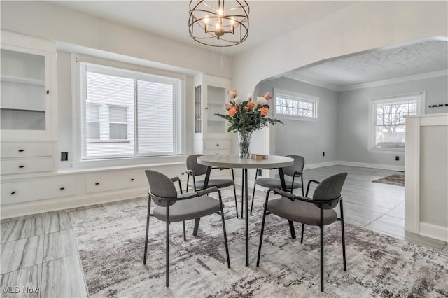 dining space featuring arched walkways, a notable chandelier, and baseboards