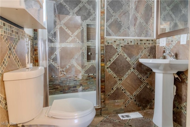 bathroom with toilet, a shower stall, and tile walls