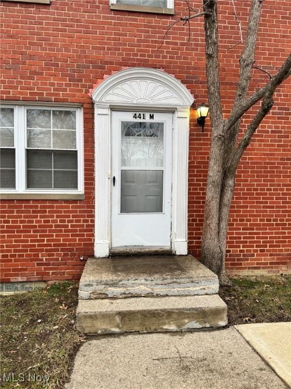 view of exterior entry featuring brick siding