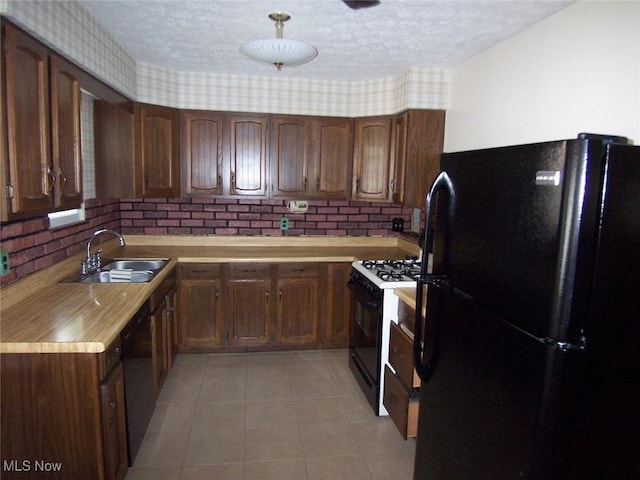 kitchen featuring light countertops, a sink, a textured ceiling, and black appliances