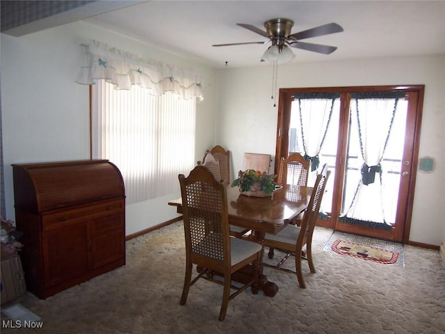 dining space featuring light carpet, ceiling fan, and baseboards