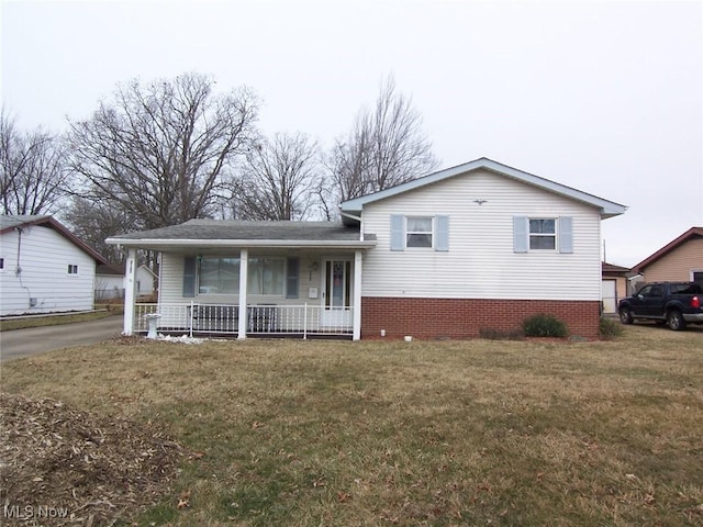 tri-level home with covered porch, a front lawn, and brick siding