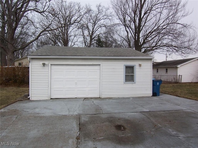 detached garage featuring concrete driveway and fence