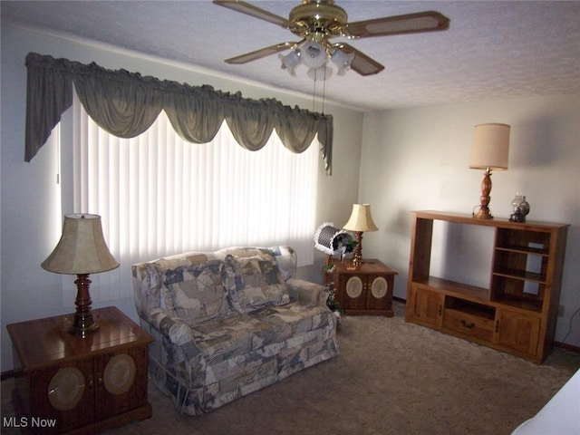 living area featuring a ceiling fan, carpet flooring, and a textured ceiling