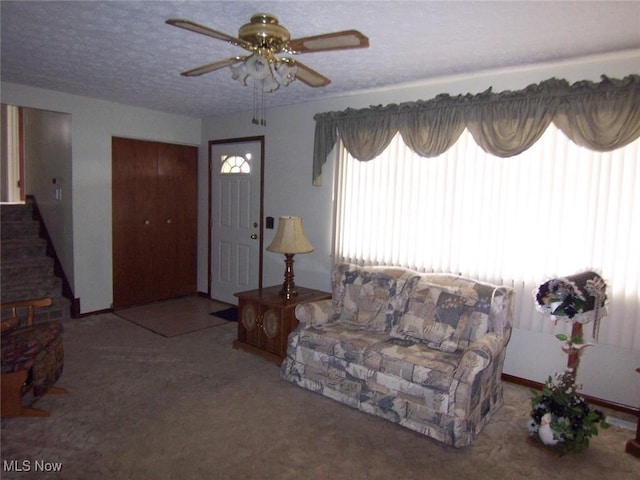 carpeted living room featuring a textured ceiling, stairway, and a ceiling fan