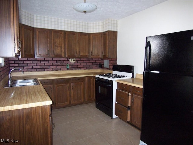 kitchen featuring a textured ceiling, black appliances, light tile patterned flooring, and a sink