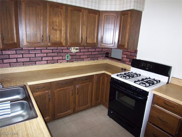 kitchen with light tile patterned floors, light countertops, a sink, and range with gas stovetop