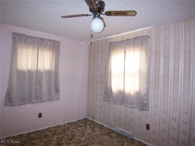 unfurnished room featuring wallpapered walls, visible vents, ceiling fan, a textured ceiling, and carpet flooring