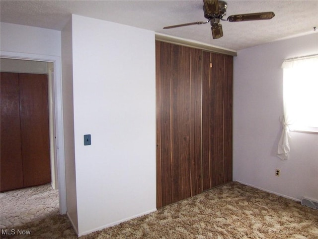 unfurnished bedroom with a ceiling fan, carpet flooring, visible vents, and a textured ceiling