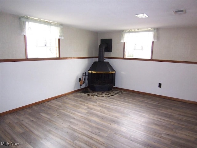 interior space with a wood stove, baseboards, and wood finished floors