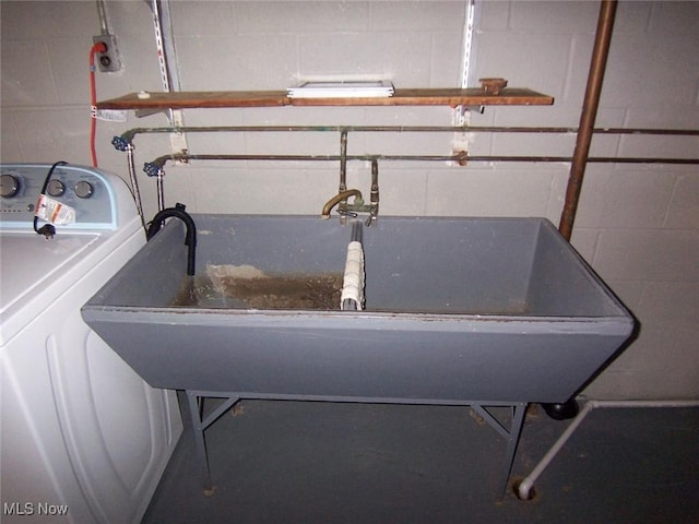 details with concrete block wall, washer / clothes dryer, and a sink