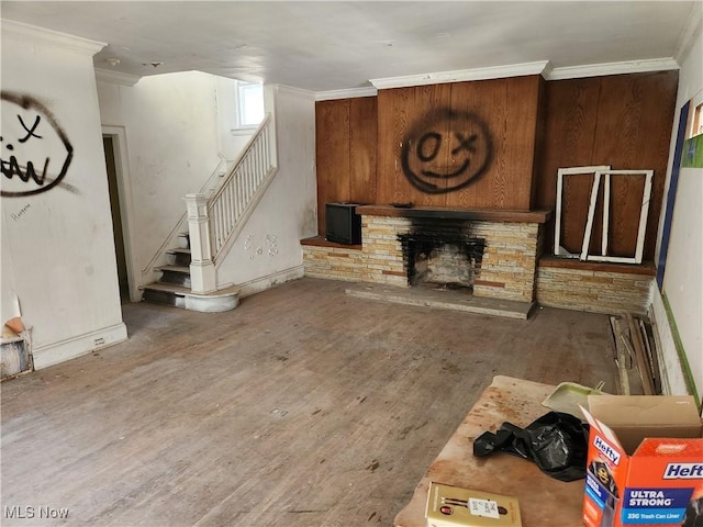 living room with stairs, ornamental molding, wood finished floors, and a stone fireplace