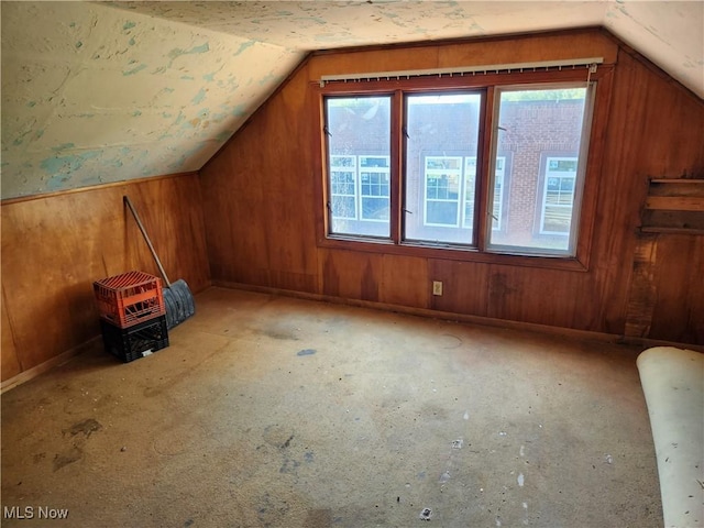 additional living space featuring lofted ceiling, wood walls, and a wealth of natural light