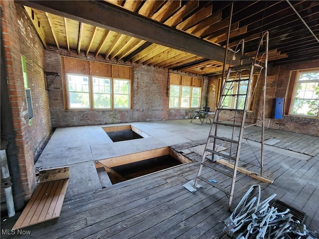 miscellaneous room with beam ceiling, hardwood / wood-style floors, and brick wall