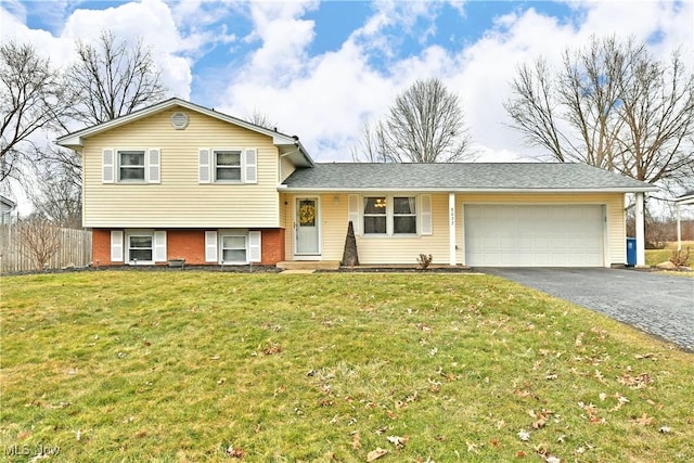 tri-level home with an attached garage, brick siding, fence, driveway, and a front yard