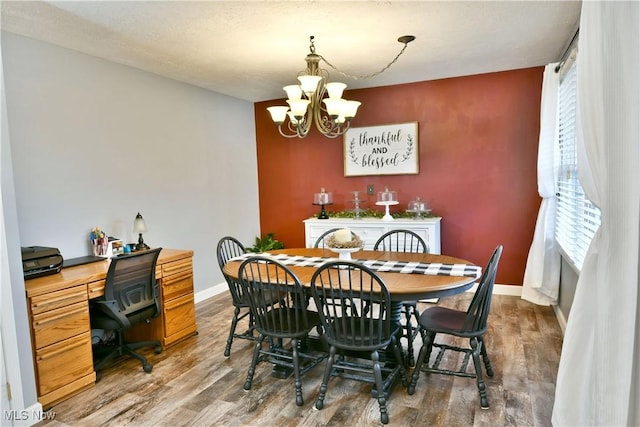 dining room featuring an inviting chandelier, wood finished floors, and baseboards