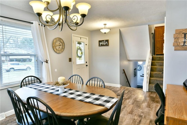 dining space with plenty of natural light, a textured ceiling, baseboards, and wood finished floors