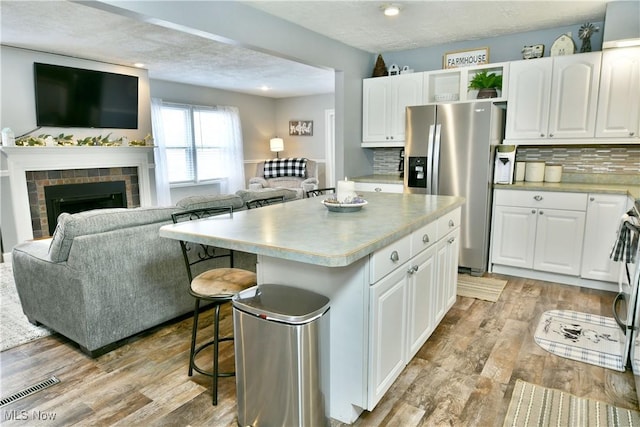 kitchen featuring open floor plan, a kitchen island, stainless steel fridge, and light wood-style flooring