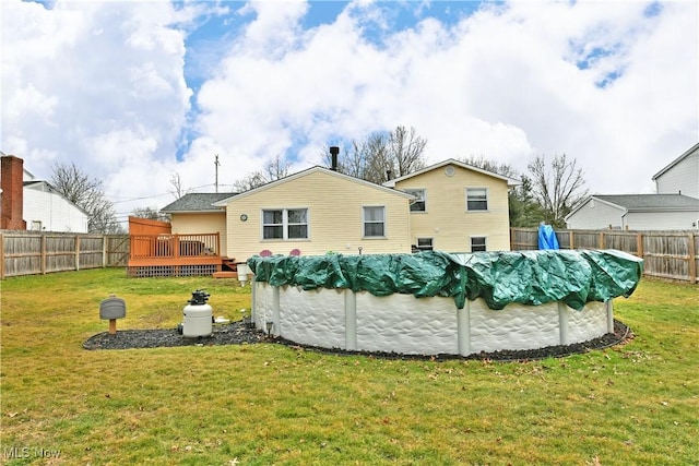 rear view of house featuring a lawn, a wooden deck, a fenced in pool, and a fenced backyard