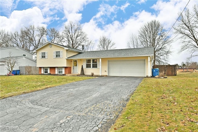 split level home with driveway, a garage, fence, and a front yard