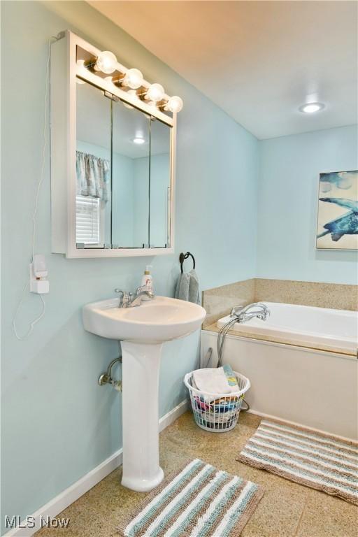 bathroom featuring baseboards and a bath