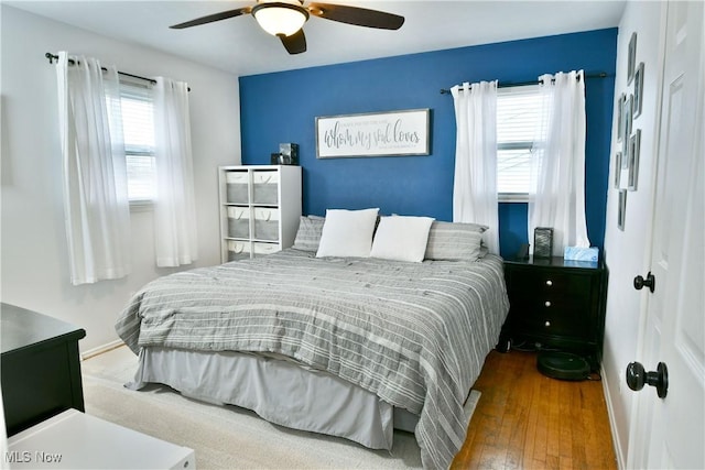 bedroom featuring wood-type flooring, multiple windows, baseboards, and ceiling fan