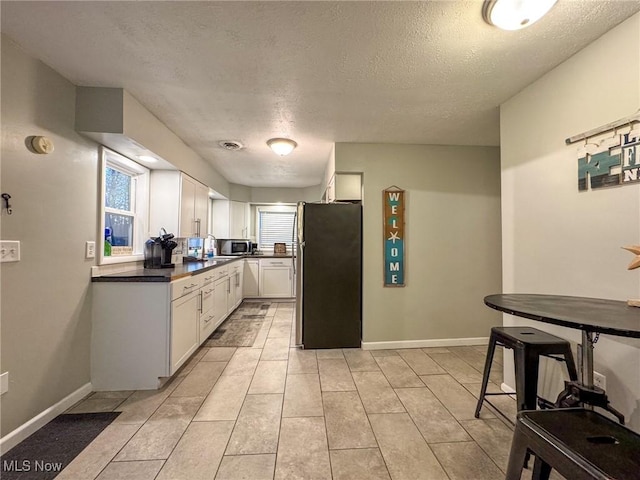 5192 University Dr, Geneva, OH 44041 - kitchen featuring appliances with stainless steel finishes, dark countertops, white cabinetry, and baseboards