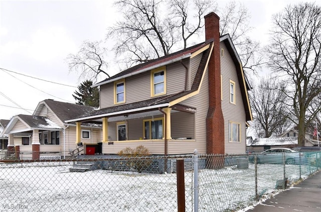 view of front facade with a fenced front yard, a porch, a chimney, and a gambrel roof