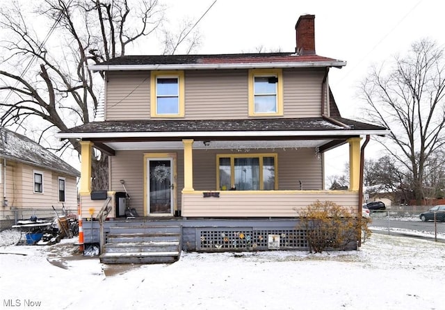 view of front of home featuring covered porch, a chimney, and fence