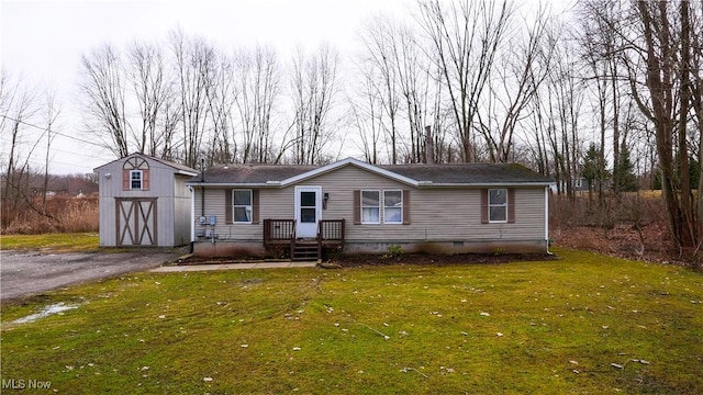 view of front facade with an outbuilding, aphalt driveway, a front yard, and a garage