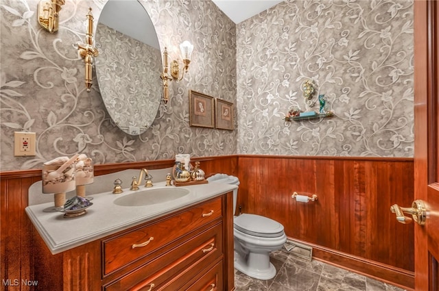 bathroom featuring visible vents, wallpapered walls, toilet, wainscoting, and vanity