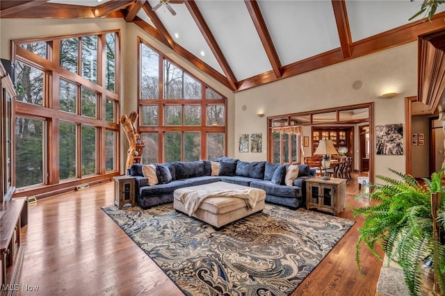 living area with beamed ceiling, high vaulted ceiling, and wood finished floors