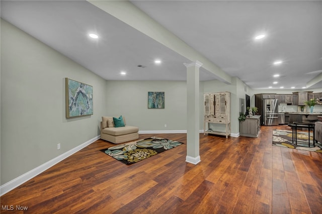 living area with dark wood-style floors, visible vents, recessed lighting, and decorative columns