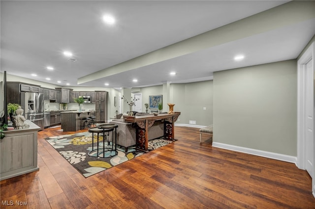 kitchen with a breakfast bar, hardwood / wood-style flooring, a center island, light countertops, and baseboards