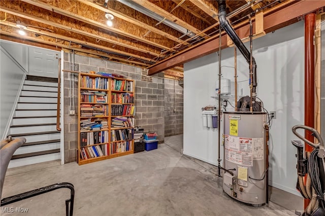 unfinished below grade area featuring gas water heater, stairway, and concrete block wall