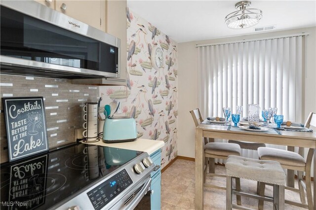 kitchen featuring appliances with stainless steel finishes, baseboards, visible vents, and decorative backsplash