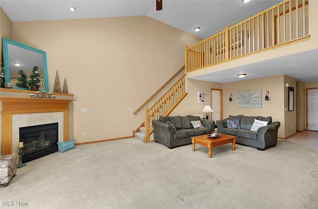 living area featuring high vaulted ceiling, a fireplace with flush hearth, carpet flooring, baseboards, and stairway