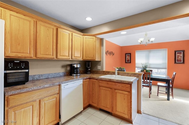 kitchen with a notable chandelier, light carpet, white dishwasher, a sink, and a peninsula