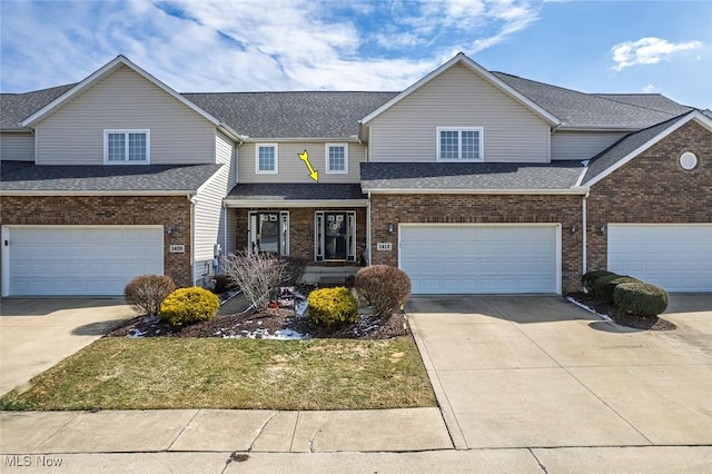 view of front facade featuring a garage, concrete driveway, roof with shingles, and brick siding