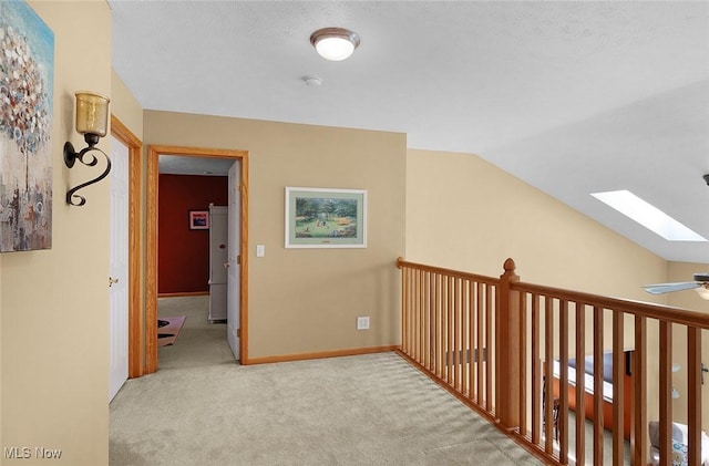 corridor with carpet, vaulted ceiling with skylight, and baseboards