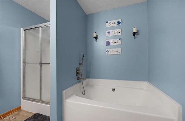 full bathroom featuring a textured ceiling, a stall shower, and a garden tub