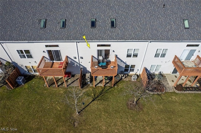 back of property featuring a shingled roof, a wooden deck, and a yard