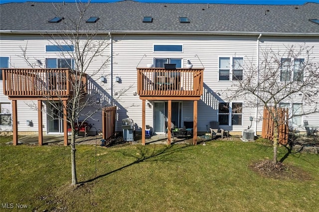 back of house with a shingled roof, central AC, and a yard