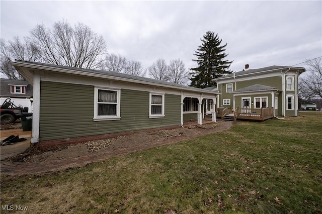 rear view of property with a deck and a lawn