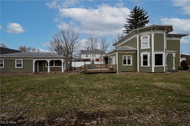 rear view of house featuring a lawn and a wooden deck